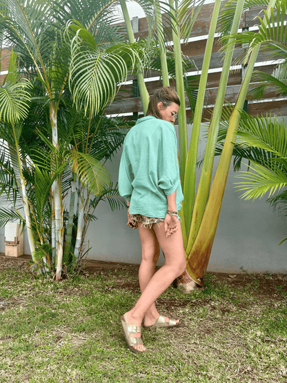 Vue de dos de la chemise oversize en voile de coton vert menthe, une pièce chic et polyvalente. Sa coupe décontractée et son tissu léger en font un essentiel pour votre garde-robe. Disponible en taille unique, achetez en ligne pour une livraison rapide directement chez vous.