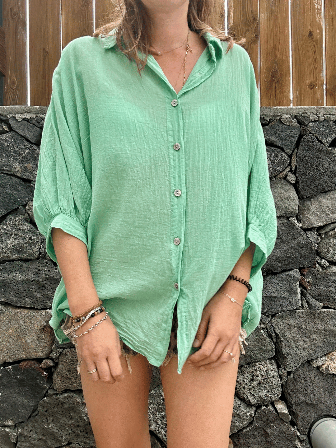Zoom sur la texture délicate du voile de coton vert menthe, d'une légèreté et d'un confort exceptionnels. Cette chemise oversize est parfaite pour les journées chaudes ou pour superposer avec vos vêtements préférés. Taille unique, à découvrir et commander en ligne dès aujourd'hui.
