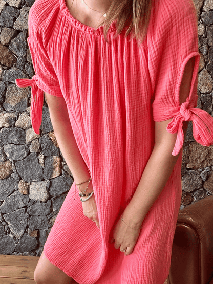 Robe corail en gaze de coton  noeud sur les bras , décolleté élastique vue de près. Disponible sur notre e-shop , livraison gratuite sur toute l'île